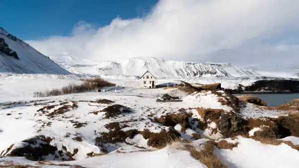 Lonely house in the middle of a snowed-in field, by the ocean